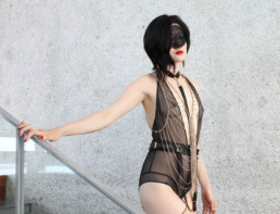 Standing in elegant chains and black lingerie, San Francisco Dominatrix Domina Yuki tempts all male submissives to serve.